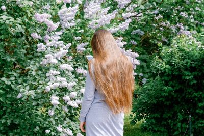 Rear view of woman standing by flowering plants