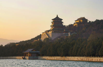 Scenic view of lake by building against sky during sunset