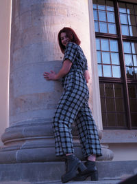 Side view of woman standing against building