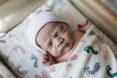 Close up detail of newborn boy swaddled with hat in hospital bassinet