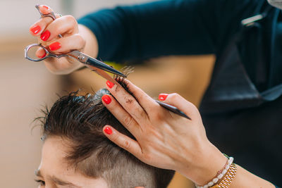 Little boy getting his hair cut by a female hairdresser in a hair salon for children.