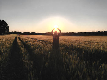 Man standing on field against sky during sunset