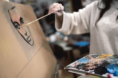 Female artist painting face on canvas at art studio