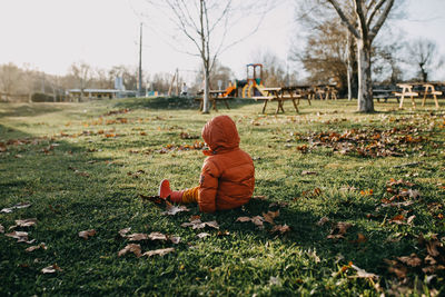 Rear view of woman sitting on grassy field