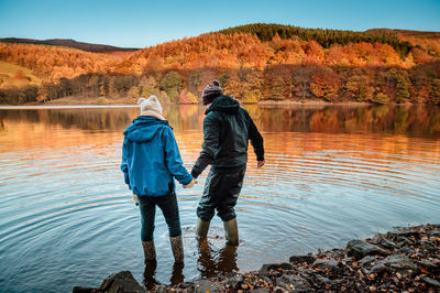 Rear view of friends standing on water at ladybower reservoir