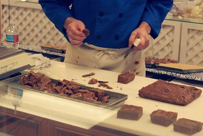 Midsection of chef preparing chocolate fudge at candy store