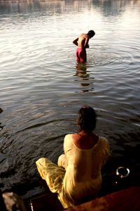 Rear view of two women sitting in lake