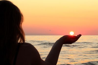 Woman looking at sea against sky during sunset