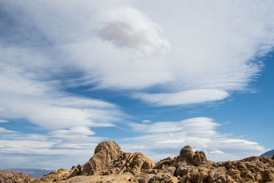 Low angle view of rocks against sky in desert with cloud layers above