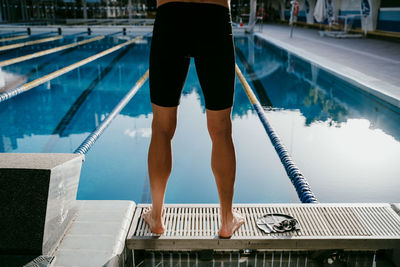 Young male swimmer standing at poolside