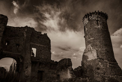 Low angle view of old ruin building against cloudy sky