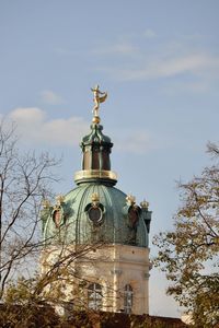 Low angle view of statue by building against sky