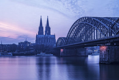 Bridge over river in city during sunset