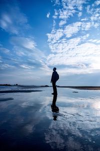 Silhouette of man standing on beach against sky