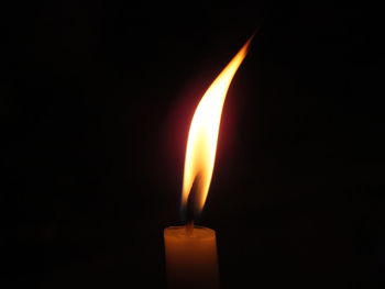 Close-up of burning candle against black background