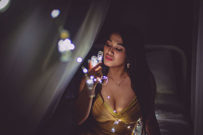 Young woman holding glass at night