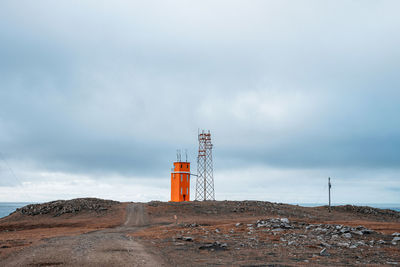 Lighthouse on road amidst buildings against sky