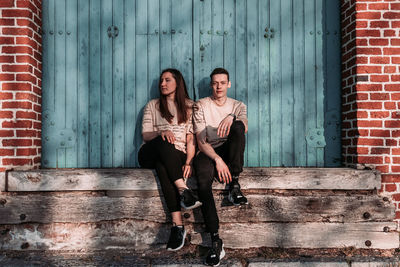 Portrait of young couple sitting on wall