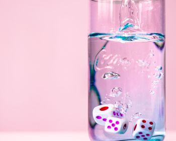 Close-up of multi colored glass on water against white background