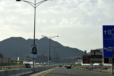 Cars on road against sky in city