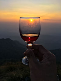 Man holding glass of sunset