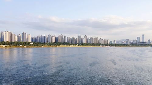 Sea by buildings against sky