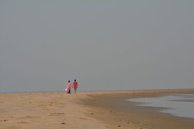 People on beach against clear sky