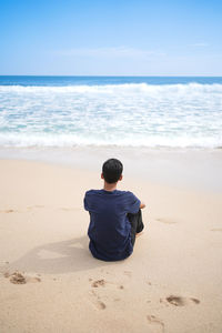 Rear view of man sitting on beach