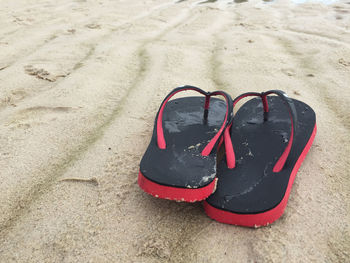 Close-up of flip-flops on sand at beach