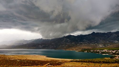 Scenic view of lake and mountains against cloudy sky