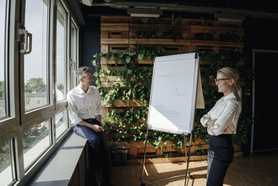 Businessman and businesswoman working with flip chart in green office