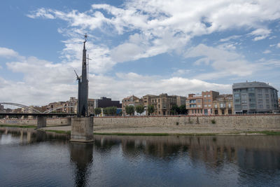 Bridge over river by buildings in city against sky