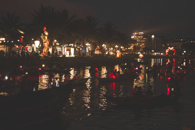 Illuminated city by river at night