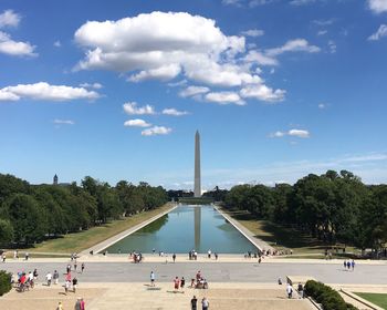 People on street in front of washington monument against sky