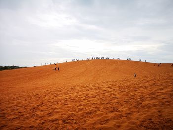 People at desert against sky
