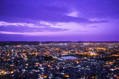 Illuminated cityscape against blue sky at night