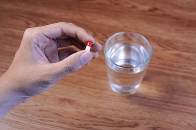 Cropped hand holding medicine over table