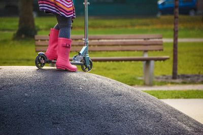 Low section of girl riding push scooter at park