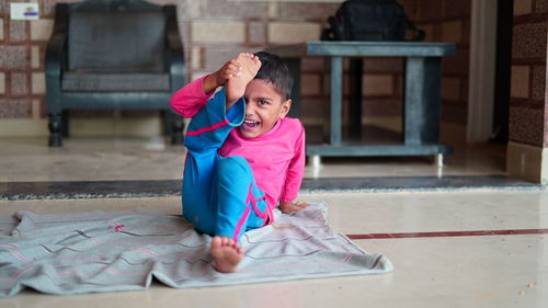  little indian boy doing yoga exercise and watching instructions on tv.. worldwide yoga day concept.