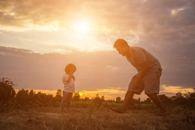 Men standing on field against sky during sunset