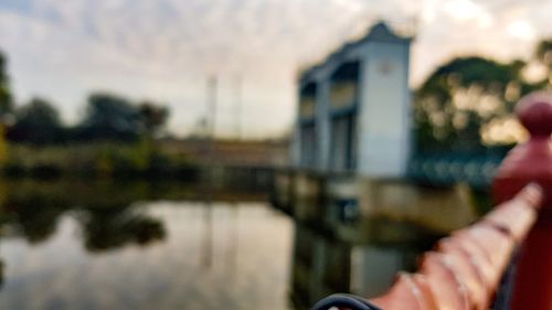 Midsection of person holding umbrella by river against building