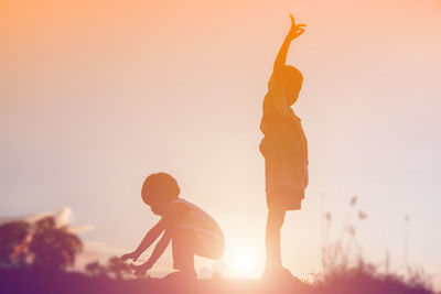 Silhouette people against orange sky during sunset