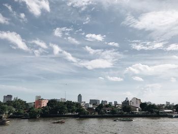 River by buildings in city against sky