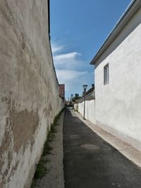 Walkway amidst houses against sky