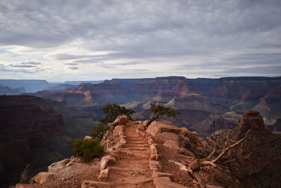Scenic view of mountain pathway leading to center of frame-  cloudy sky in background.