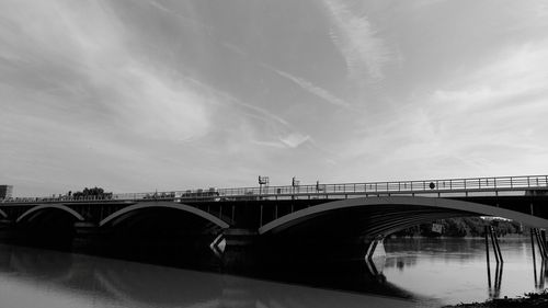 Arch bridge over river in city against sky