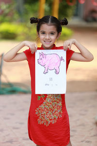 Portrait of girl showing pig drawing on paper