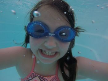 Portrait of smiling girl wearing swimming goggles in pool
