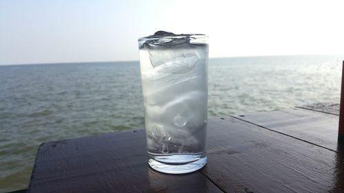 Close-up of drink on table by sea against clear sky