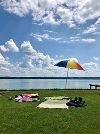 Umbrellas on field by sea against sky